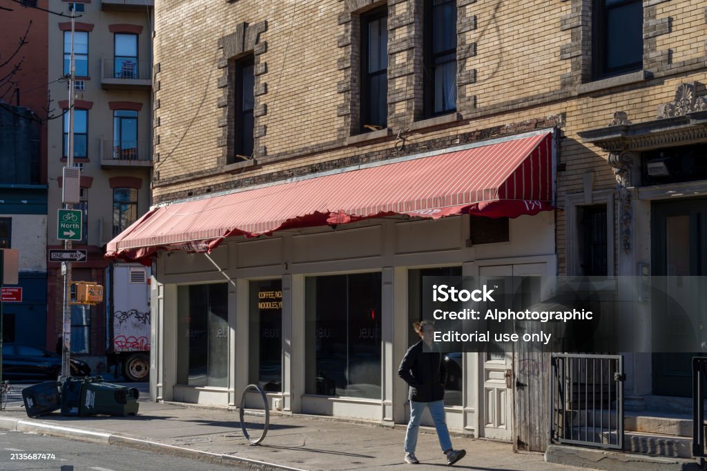 Store banne avec toile décolorée et lambrequin déchiré devant une vitrine de commerce